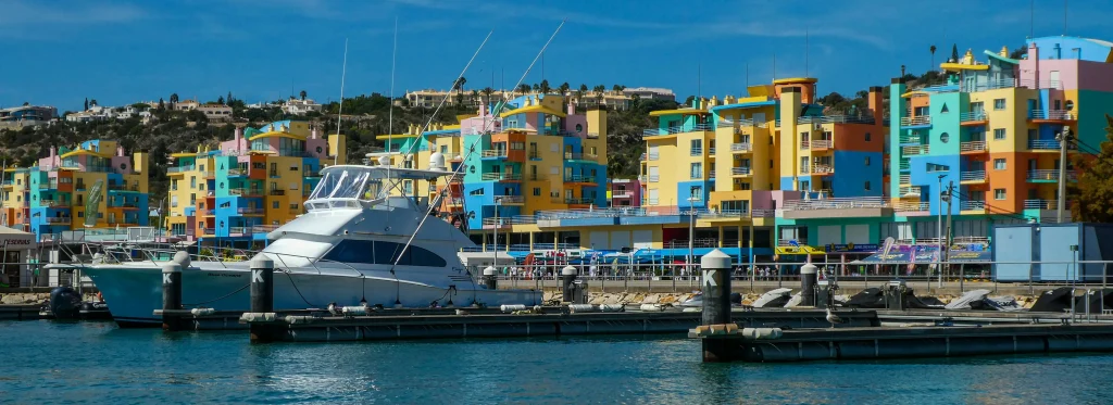  Bâtiments colorés et bateaux au port d’Albufeira, une destination incontournable pour des vacances en Algarve au Portugal.